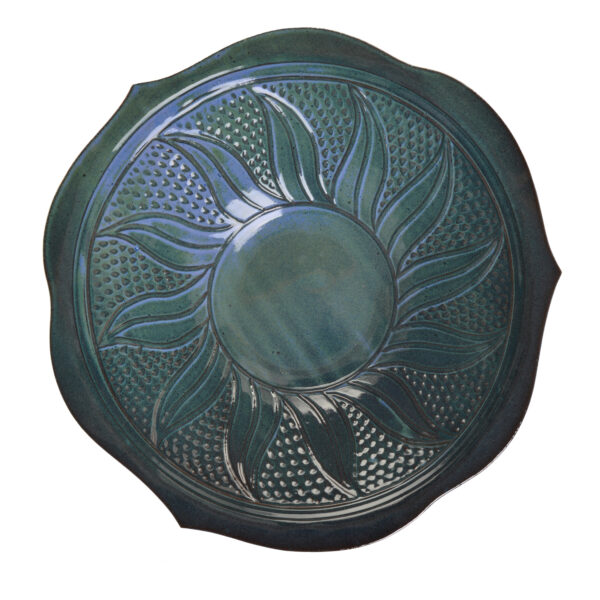 Medium blue ceramic slab-built serving bowl with a sunflower like silhouette accented with dots filling the interior. A beautiful blue and green glaze highlights the surface decoration.