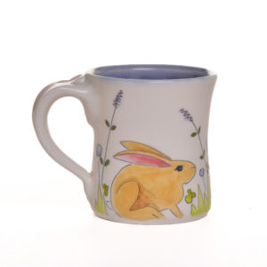 Small mug decorated with bunnies and flowers. When artist Meghan Bernard created this design, she was inspired by all the bunnies that hangout around her new studio. Each piece is thrown porcelain on the wheel and then carved. After each piece dries the black lines are carved into the porcelain with a sharp knife, then inlaid with black under-glaze. Each color is hand painted before being glazed with food safe glazes.