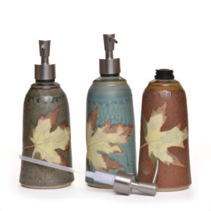 Wheel-thrown lotion or soap dispenser with a leaf decoration. Artist Travis Berning creates his tumblers on the potter’s wheel, then adds a leaf decoration. The dispensers are dipped in a wood-ash glaze. Different glazes to chose from.