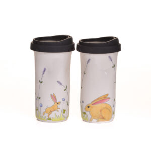 Enjoy your favorite beverage on the go in a sweet and cheerful bunny travel mug. When artist Meghan Bernard created this design, she was inspired by all the bunnies that hangout around her new studio. Each piece is thrown porcelain on the wheel and then carved. After each piece dries the black lines are carved into the porcelain with a sharp knife, then inlaid with black under-glaze. Each color is hand painted before being glazed with food safe glazes.
