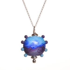 This swirled blue and purple handmade glass bead pendant is inspired by the works of Van Gogh. Teresa Brittain creates glass beads over a torch, using the centuries-old technique of lampworking, then combines the beads with sterling silver findings and chains to create unique pieces of wearable art.