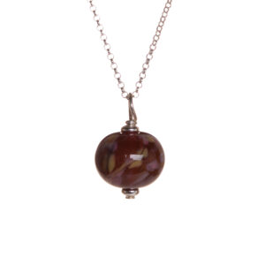 Mini cranberry glass bead with frit pendant created over a torch. Teresa Brittain creates glass beads over a torch, using the centuries-old technique of lampworking, then combines the beads with sterling silver findings and chains to create unique pieces of wearable art.
