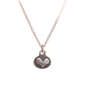 This dainty silver relief heart pendant is cast from a granulated original and cast using the lost wax process. Susan cuts out a heart of fine silver and fuses it to an oval background using the ancient fusing process of granulation. 
