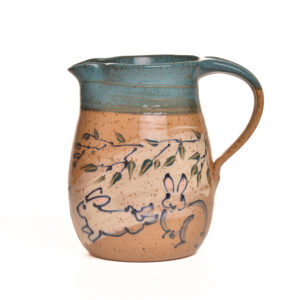 Large pitcher with hand-painted bunnies on either side and a sage green glaze on the inside and rim.