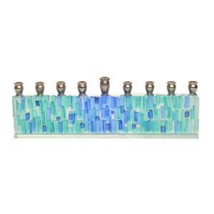 Menorah fused in blue and aqua-toned textured glass, with dichroic speckles. Artist Alicia Kelemen fuses the colorful glass together, then laminates it to a glass surface in a light greenish tone, and adds silver metal tops.