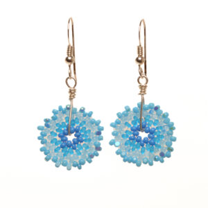 Round disk earrings featuring handwoven glass seed beads by jeweler Leslie Fawcett of Tennessee. With a needle and nylon thread, Leslie takes tiny glass seed beads and weaves them into larger beads that are then rolled up and sewn together. The use of the peyote stitch allows the ends of the rectangle to interlock when sewn together, and repeated passes through the beads reinforce the whole.