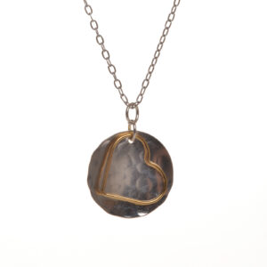 Handcrafted gold-filled heart on sterling silver hammered disc pendant by silversmith Suzanne Farran-Hrytzik of North Carolina. This piece features a free flowing heart dancing on a brilliantly shining disc. Great for everyday wear. Expect slight variations in design. Matching earrings available.