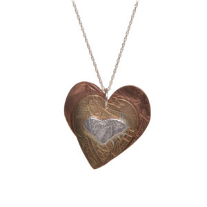 Handcrafted mixed metal heart necklace by silversmith Suzanne Farran-Hrytzik of North Carolina. This piece features contrasting embossed and layered hearts made of copper, gold-fill, and sterling silver. Great for everyday wear. Expect slight variations in design.