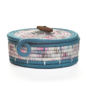 Handmade coiled rope basket by artist Ann Oakes of North Carolina. Each basket is a vibrant and unique piece of textile art. The durable rope core is meticulously wrapped in yarn, forming an eye-catching spiral design with cool tones. A sweet lid accented with a bead toggle adds a charming, artisanal touch, making it a perfect functional art piece for any home. Spot clean with a damp cloth or vacuum with a small vacuum cleaner.