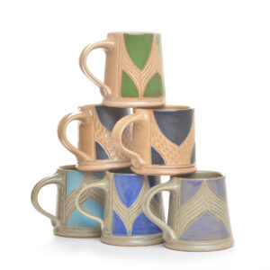 Short wheel-thrown stoneware mug that combines functional design with intricate botanical artistry by North Carolina potter Robin Kirby Bryant. The original designs are hand-carved and painted on each piece. No two are alike, though they will share the feeling of belonging together. Dishwasher and microwave-safe. Different colors and designs available. Each sold separately.