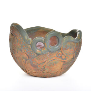 This richly textured and earthy glazed stoneware bowl is perfect for serving or as a decorative statement piece for any table or kitchen, created by North Carolina potter Rebecca Regal. Her ceramics combine hand-building, wheel-throwing, and sculptural techniques, drawing inspiration from Appalachian nature, folklore, and rustic charm. Most of the glazes she uses are original glaze recipes curated by her potter father for over 50 years. Each piece is produced in small batches and is one of a kind.