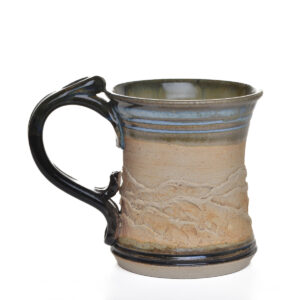 This handcrafted stoneware mug features a carved and textured mountain landscape that wraps around each piece, created by North Carolina potter Rebecca Regal. Her ceramics combine hand-building, wheel-throwing, and sculptural techniques, drawing inspiration from Appalachian nature, folklore, and rustic charm. Most of the glazes she uses are original glaze recipes curated by her potter father for over 50 years.. Each piece is produced in small batches and is one of a kind. Different glaze options available. Each sold separately.