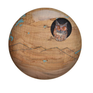 Bring the beauty of the wilderness into your home with this handcrafted circular wood plaque, featuring polished grain, etched mountain peaks, and vibrant inlaid turquoise resin accents. A detailed, hand-painted owl peers out from a knot hole, creating a unique piece of rustic, nature-inspired décor. Bring some nature indoors and have it all year long! Expect slight variations.